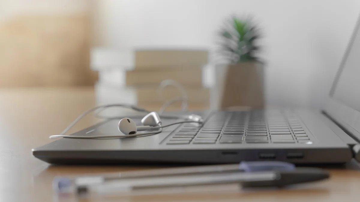 Laptop, headphones, and writing materials arranged for a telehealth appointment.