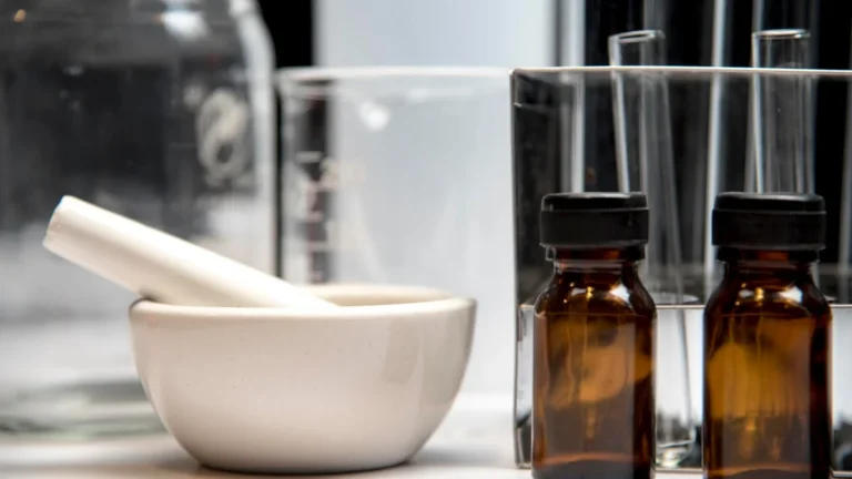 Mortar, pestle, and amber bottles in a compounding laboratory setting.