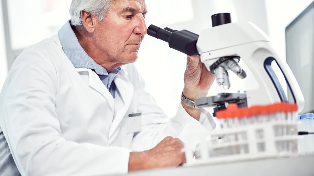 Laboratory scientist examining a prepared sample through a microscope.